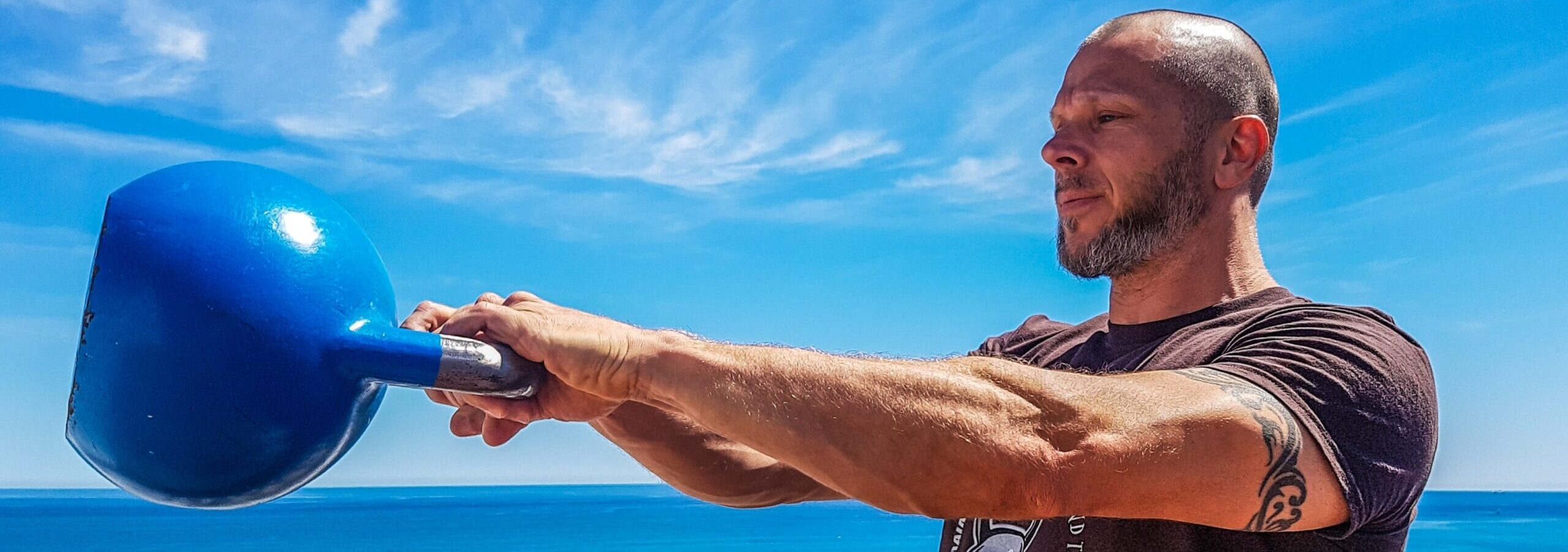 Bilden visar en person med en kettlebell. Kettlebells är en viktig del av ett hemmagym.